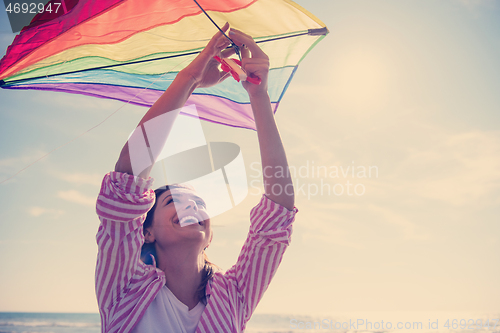 Image of Young Woman with kite at beach on autumn day