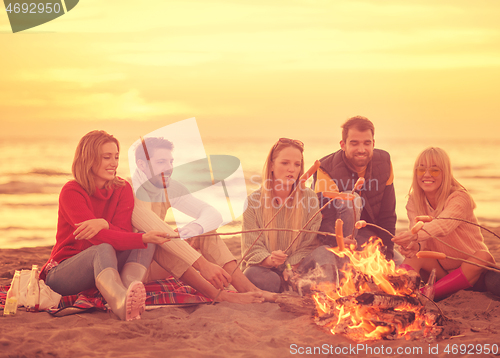 Image of Group Of Young Friends Sitting By The Fire at beach