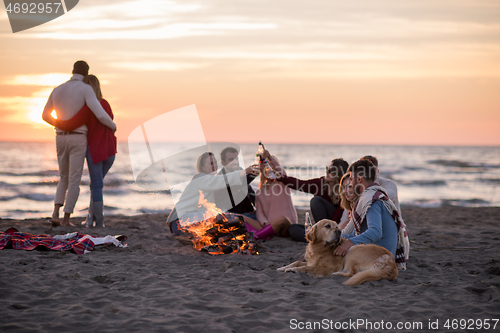 Image of Couple enjoying with friends at sunset on the beach