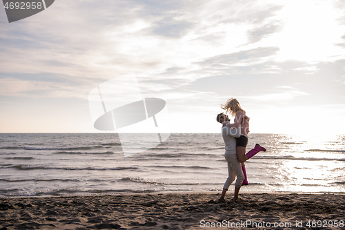 Image of Loving young couple on a beach at autumn sunny day