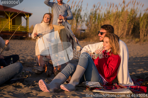 Image of Couple enjoying with friends at sunset on the beach