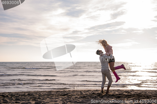 Image of Loving young couple on a beach at autumn sunny day