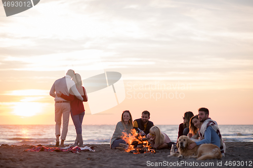 Image of Couple enjoying with friends at sunset on the beach