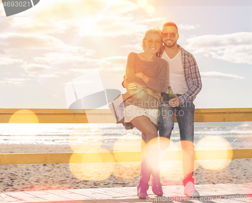 Image of young couple drinking beer together at the beach