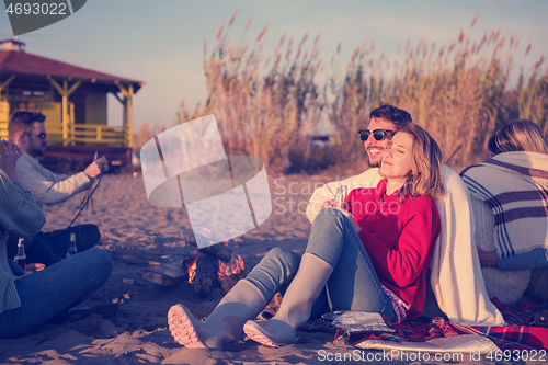 Image of Couple enjoying with friends at sunset on the beach