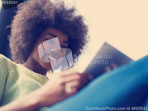 Image of young african american woman at home using digital tablet