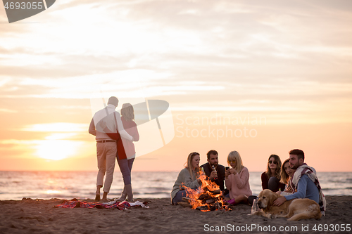 Image of Couple enjoying with friends at sunset on the beach