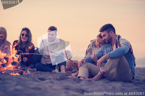 Image of Group Of Young Friends Sitting By The Fire at beach