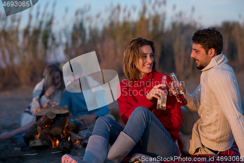 Image of Couple enjoying with friends at sunset on the beach