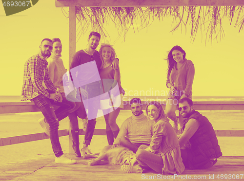 Image of Group of friends having fun on autumn day at beach