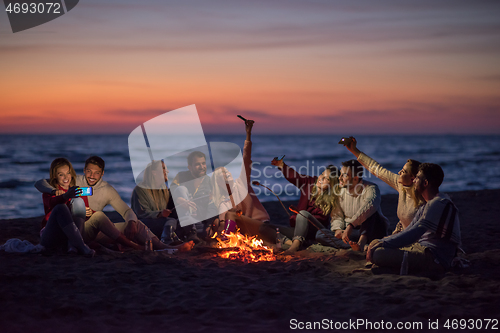 Image of a group of friends enjoying bonfire on beach