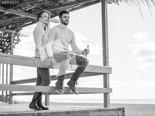 Image of young couple drinking beer together at the beach