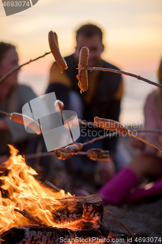 Image of Group Of Young Friends Sitting By The Fire at beach