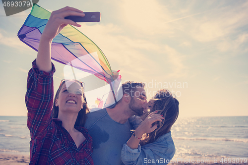 Image of Group of friends making selfie on beach during autumn day