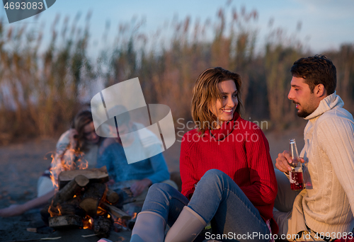 Image of Couple enjoying with friends at sunset on the beach