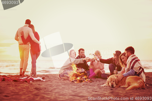 Image of Couple enjoying with friends at sunset on the beach