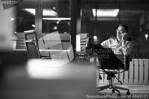 Image of businessman using mobile phone in dark office