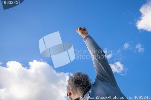 Image of bearded man pointing up to the blue sky