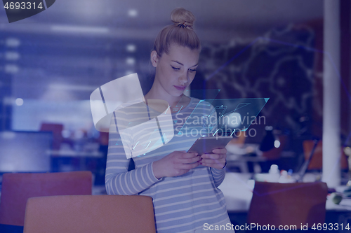 Image of woman working on digital tablet in night office