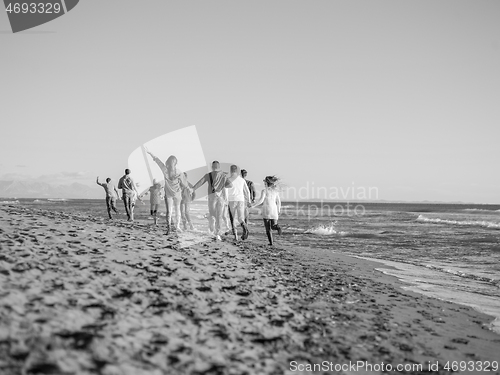 Image of Group of friends running on beach during autumn day