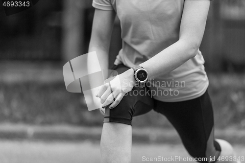 Image of female runner warming up and stretching before morning training