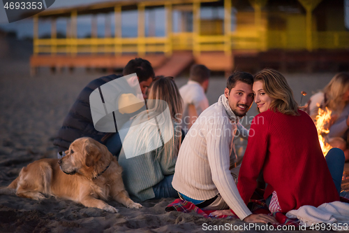 Image of Couple enjoying with friends at sunset on the beach