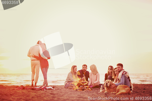 Image of Couple enjoying with friends at sunset on the beach