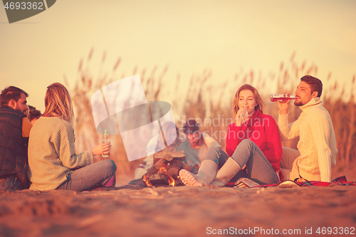 Image of Couple enjoying with friends at sunset on the beach