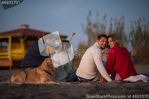 Image of Couple enjoying with friends at sunset on the beach