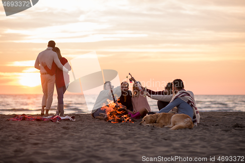 Image of Couple enjoying with friends at sunset on the beach