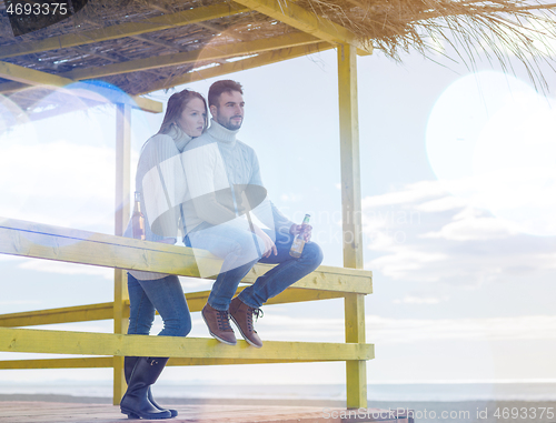 Image of young couple drinking beer together at the beach