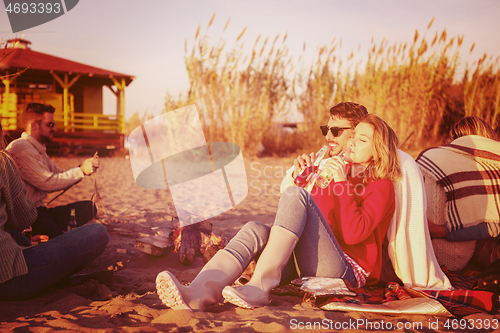 Image of Couple enjoying with friends at sunset on the beach