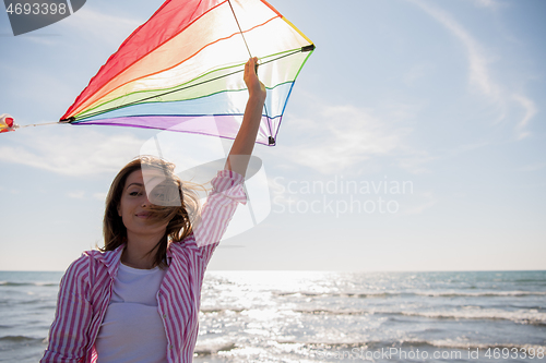 Image of Young Woman with kite at beach on autumn day