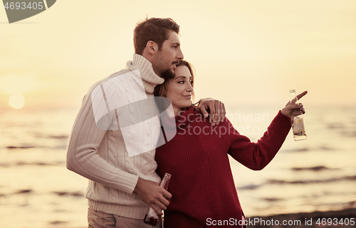 Image of Couple hugging and drinking beer together at the beach