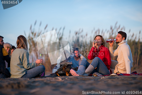 Image of Couple enjoying with friends at sunset on the beach