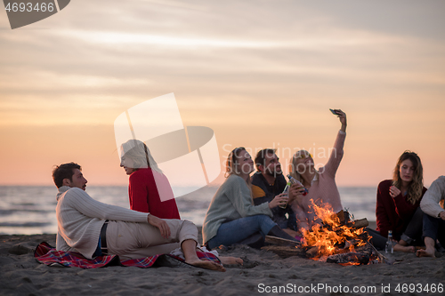 Image of Friends having fun at beach on autumn day