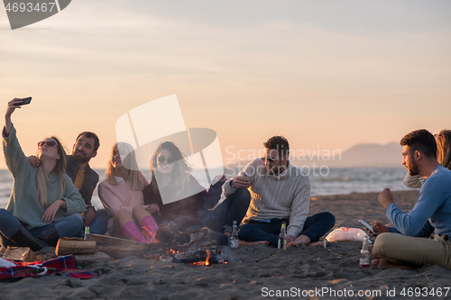 Image of Friends having fun at beach on autumn day