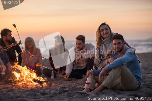 Image of Group Of Young Friends Sitting By The Fire at beach