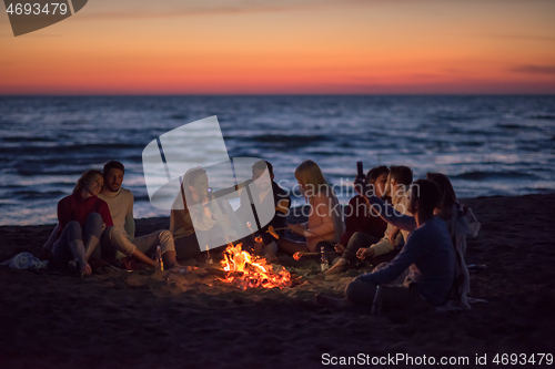 Image of a group of friends enjoying bonfire on beach