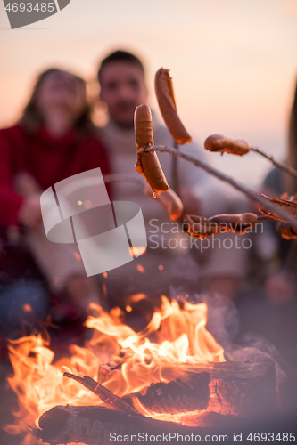 Image of Group Of Young Friends Sitting By The Fire at beach