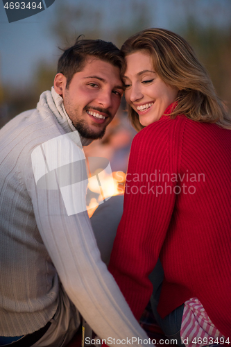 Image of Couple enjoying with friends at sunset on the beach