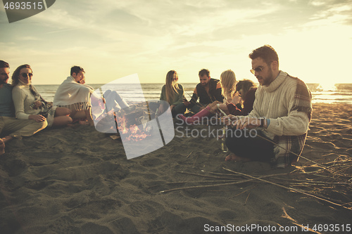 Image of Friends having fun at beach on autumn day