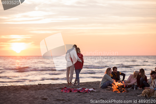 Image of Couple enjoying with friends at sunset on the beach