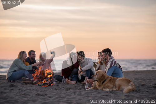 Image of Friends having fun at beach on autumn day