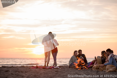 Image of Couple enjoying with friends at sunset on the beach