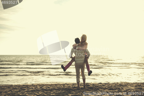 Image of Loving young couple on a beach at autumn sunny day