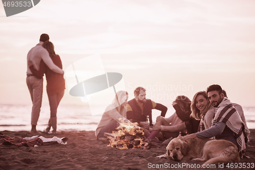 Image of Couple enjoying with friends at sunset on the beach