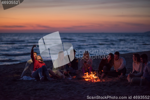 Image of a group of friends enjoying bonfire on beach