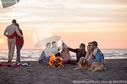 Image of Couple enjoying with friends at sunset on the beach