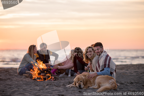 Image of Couple enjoying with friends at sunset on the beach